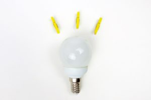 Lightbulb on white background surrounded by three yellow clothes pegs