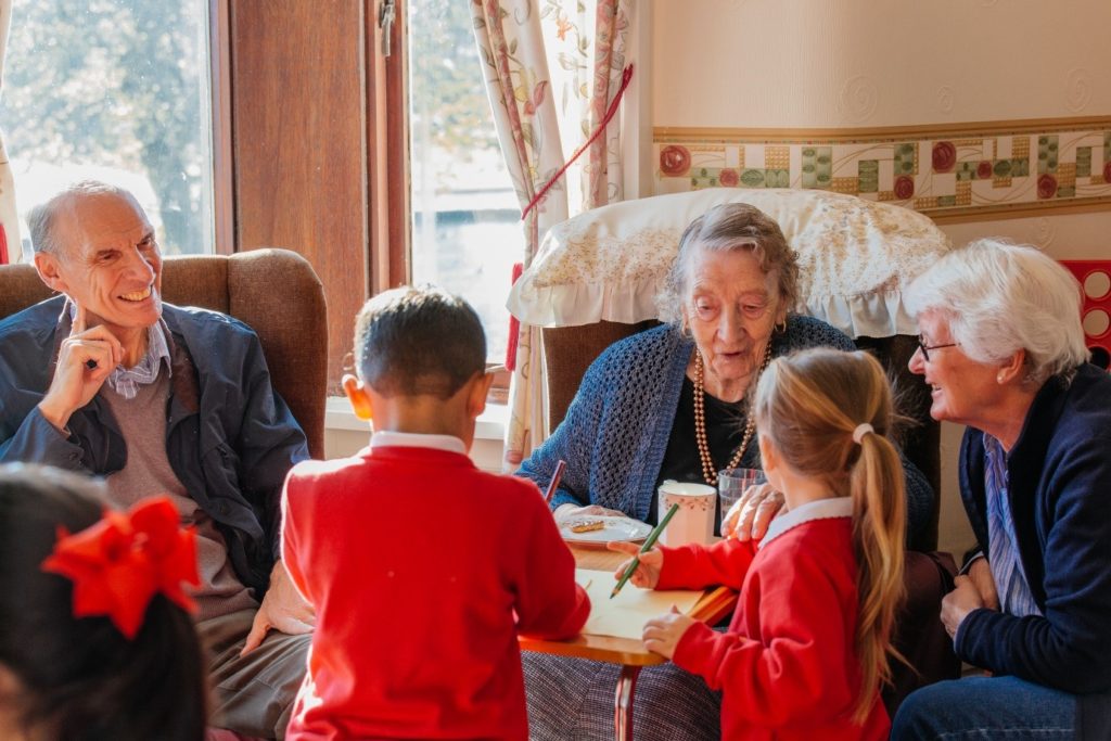Two children interacting with older care home residents