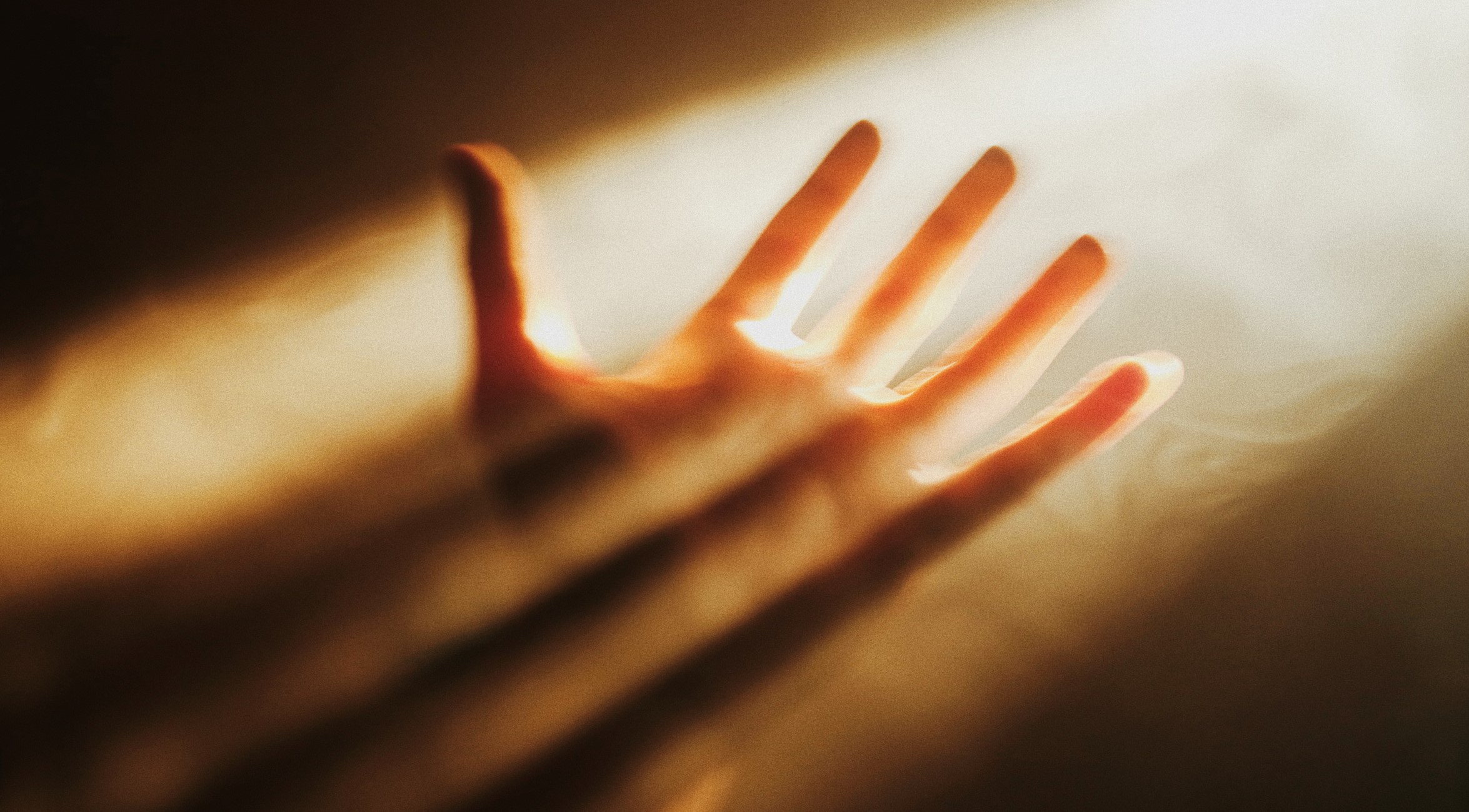 Photo of human left hand in stream of light