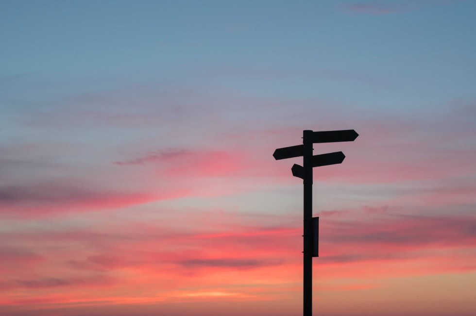 Silhouette of a signpost against a sunset sky