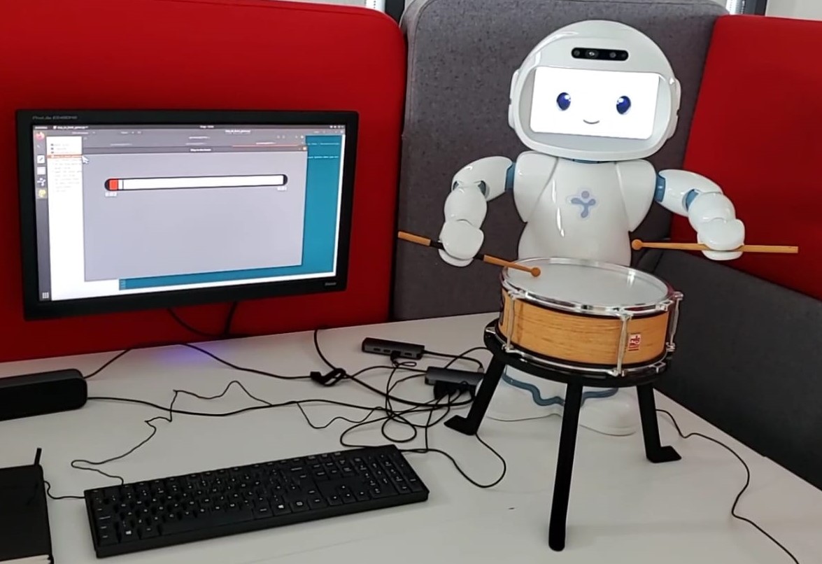 Small humanoid robot drumming with drumsticks