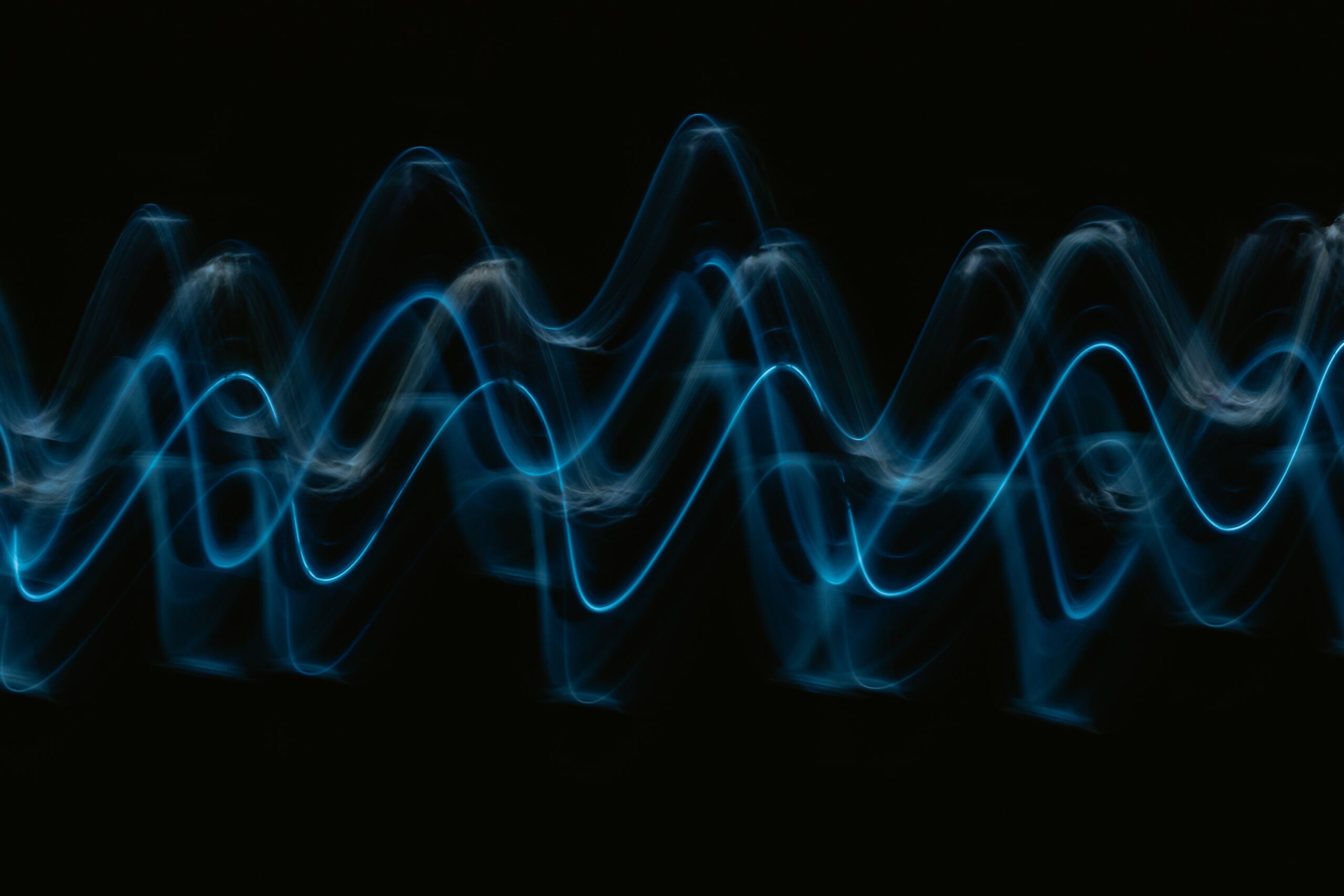 Abstract waves of blue light against a dark background.