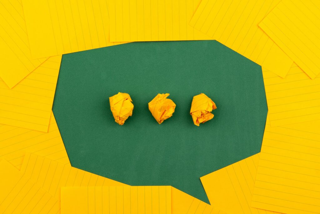 Orange sheets of paper arranged on a green background to form a speech bubble.